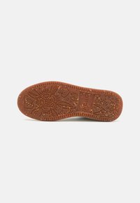 Rubber shoe sole in terracotta with intricate floral and leaf patterns. Textured surface, slightly raised edges, and speckled design.
