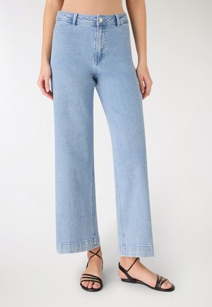 Jeans a gamba larga di colore azzurro chiaro in denim con vita alta, caratterizzati da chiusura con bottone, tasche frontali e orlo netto. Abbinati a sandali neri.
