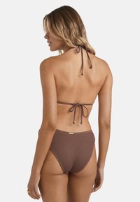 Top bikini in crochet marrone con chiusura a stringa sul retro e slip a vita alta, caratterizzato da un tessuto testurizzato e un accentuato hardware metallico minimal.