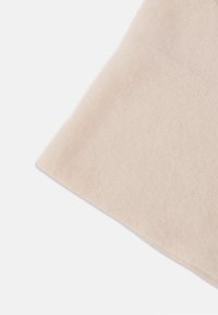 Béžová pletená látka s jemnou textúrou, s čistým, rovným okrajom. Povrch vykazuje jemný, rovnomerný vzor.