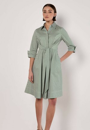 Green and white striped shirt dress with a collar, button-down front, waist tie, and three-quarter sleeves. Flared skirt with vertical lines.