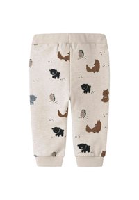 Pantalons de survêtement beige clair avec des motifs d'animaux, présentant des illustrations noires, brunes et grises de renards, hérissons et ours. Ceinture élastique.