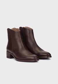 Botas de piel marrón hasta el tobillo con una textura suave, puntera ligeramente puntiaguda, cremallera lateral y un diseño de taco bajo cuadrado.
