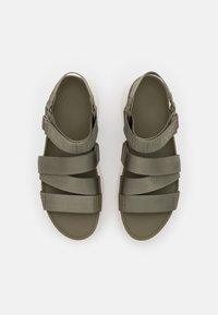 Olivově zelené sandály s nastavitelnými textilními popruhy a strukturovaným designem. Úzká, plochá podešev s bílým okrajem a vyraženým logem na vložce.