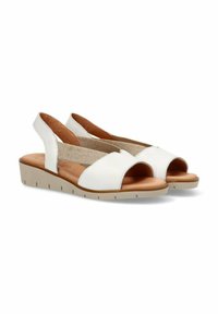 Sandalias de piel blancas de punta abierta con una plantilla de color marrón claro, una correa media elástica para mayor comodidad y una suela de goma beige texturizada y baja.