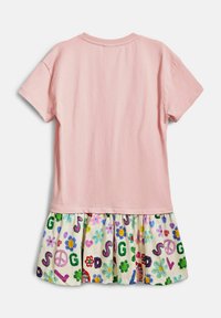 Rosa kortärmad topp med en vit mönstrad kjol som har färgglada blommor, fredstecken och bokstäver i olika livliga färger.