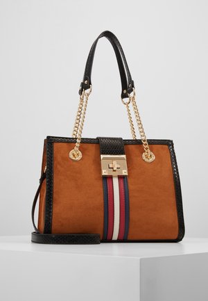 Bruine suède handtas met zwarte afwerking, gouden kettinghengsels, een gouden sluiting en verticale rode, witte en marineblauwe strepen aan de voorkant.