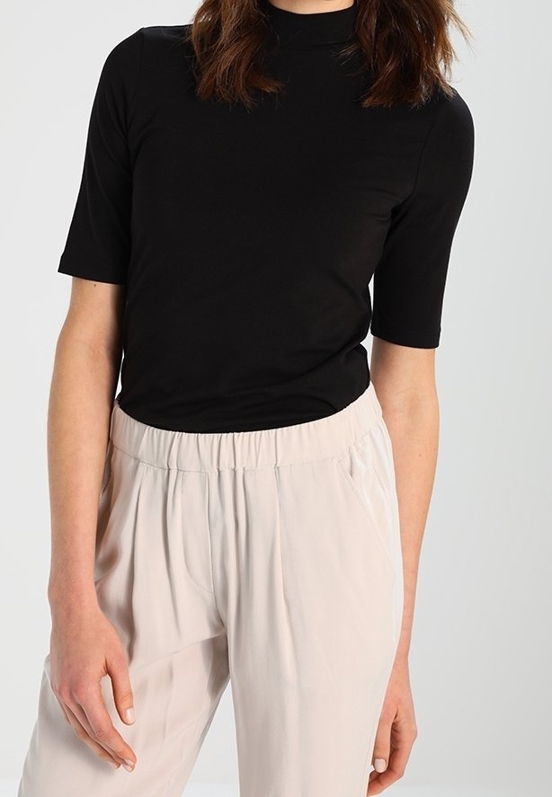 Sort T-shirt med høj hals og korte ærmer i en glat kvalitet, parret med lysebeige, løstsiddende bukser med elastisk talje.