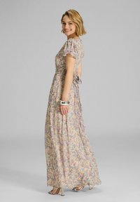 Maxikleid aus leicht beige farbenem Stoff mit einem floralen Muster in lila und blau. Verfügt über kurze, leichte Ärmel und ein Bindeband im Rücken.