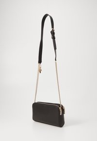 Schwarze Leder-Crossbody-Tasche mit glatter Textur, goldener Kettenriemen, doppeltem Reißverschluss und Schlüsselakzentdetail. Einfaches rechteckiges Design.