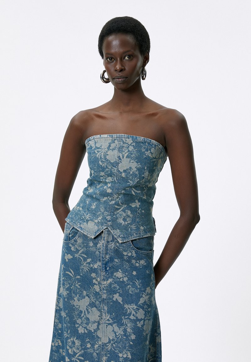 Denim floral corset-top har et tætsiddende design med en lige halsudskæring og dekorativ syning. Sammen med en matchende lang nederdel.