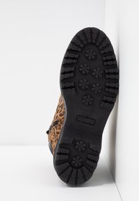 Stivale marrone con stampa leopardata, superficie testurizzata, suola in gomma nera con un motivo di battistrada robusto e dettaglio con zip laterale.