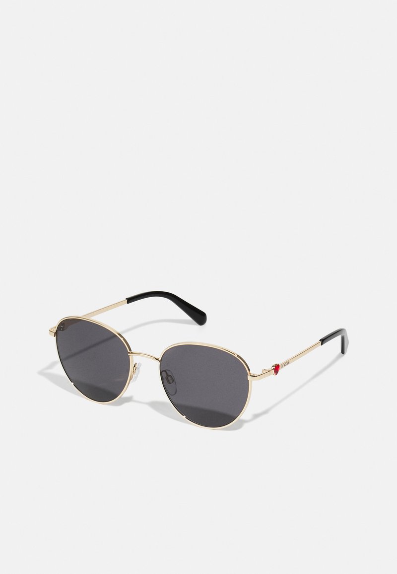 Gold-framed sunglasses with grey lenses, oval shape, featuring black temple tips and a red accent detail on the right side.