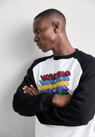 Czarny i biały sweatshirt z wielokolorowym graficznym napisem "MOSCHINO". Ma długie rękawy i klasyczny dekolt typu crew.