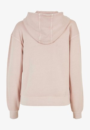 Rozā kapuce ar mīkstu tekstūru, ar auklā velkamu kapuci, izteiktām plecu šuvēm un ribotām aprocēm. Izceļas ar minimālistisku dizainu bez priekšējo detaļu.