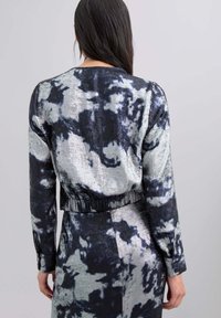 Indumento a motivo nero e grigio con design corto, maniche lunghe e vita elastica, caratterizzato da una finitura in tessuto liscia e testurizzata.