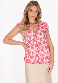 Blomstret bluse i cremede farver med rosa bladmønstre, korte flæseærmer og V-udskæring, lavet af letvægtigt stof for komfort.