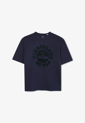 Tamsiai mėlynas medvilninis marškinėliai su apvalia iškirpte ir trumpomis rankovėmis. Viduryje yra žalia grafika su logotipo ir užrašu "Timberland USA".