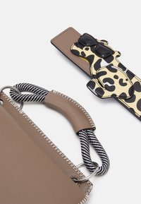 Braune Lederhandtasche mit einem gestreiften Seilgriff, featuring einer schwarzen und gelben gepunkteten Verzierung in Form eines Hundes, der Sonnenbrillen trägt.