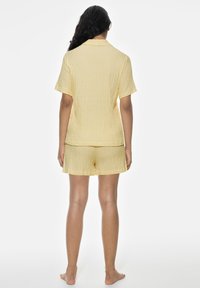 Gulrutigt tvådelat sovset med korta ärmar och shorts, med ett texturerat tyg som har ett rutmönster.