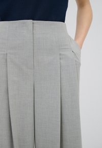 Lichtgrijze geplisseerde broek van een gestructureerde stof, met zijzakken en een middenhoogte taille voor een op maat gemaakte look.