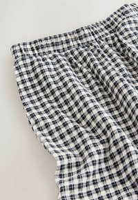 Schwarz-weiß kariertes Gewebe mit strukturierter Oberfläche, einem gerafften Taillenbund und komplexen Webmustern.