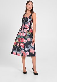 Ein ärmelloses, knielanges schwarzes Kleid mit einem floralen Muster in Pink und Grün, das einen quadratischen Ausschnitt und eine ausgestellte Silhouette aufweist.