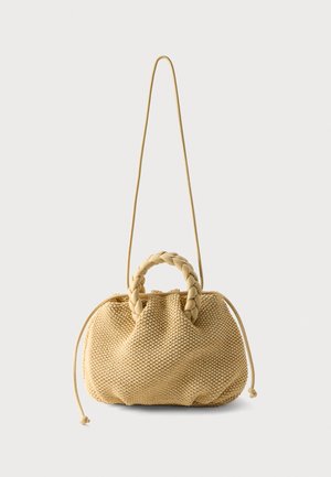 Beige geweven handtas met gevlochten bovenhandvatten, tunnelzijden met trekkoord en een lange dunne schouderriem op een effen witte achtergrond.