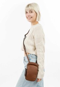 Brown leather crossbody bag with a zippered pocket, featuring a smooth texture and adjustable strap. Compact rectangular shape.