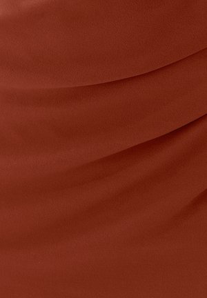 Ruosteenvärinen kangas, jossa on sileä tekstuuri ja kerroksittain laskeutuva laskostus, joka muodostaa pehmeitä, virtaavia linjoja pinnalle.