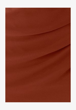 Tkanina boje hrđe s glatkom teksturom, s višeslojnim naborima koji stvaraju mekane, tekuće linije preko površine.