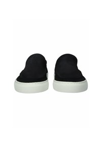 Par de zapatos negros sin cordones con suelas de goma blanca vistos desde el frente sobre un fondo blanco.