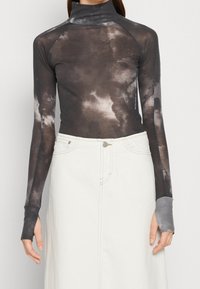 Pitkähiha, vartalonmyötäinen tummanharmaa poolopaita, jossa on pilvimäisiä valkoisia kuvioita; sisältää peukalonreiät hihoissa, valmistettu pehmeästä, kevyestä materiaalista.