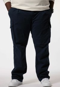Navy cargobroek met een ontspannen pasvorm, voorzien van meerdere zakken, gestikte details en een gladde, zachte textuur. Draagt met witte sneakers.