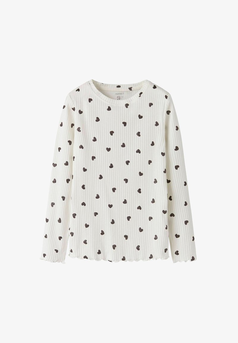 Pikakäised valge topp ribatud kangast, millel on väiksed pruunid südame mustrid, lainelise äärega ja ümmarguse kaelusega.