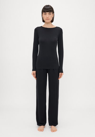 Haut noir à manches longues et pantalon large en tissu doux, avec un col rond simple et un design minimaliste.
