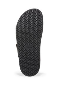 Svart gummisko sula med en strukturerad fiskbensmönster. Har en etikett med texten "Cole Haan GRAND 360" i mitten.