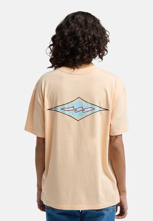 Maglietta oversize color pesca con grafica a diamante blu e nera sul retro, realizzata in tessuto morbido e leggero.