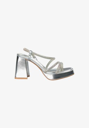 Silberner High-Heel-Sandalette mit Blockabsatz, ausgestattet mit überkreuzten Riemen, die mit Strasssteinen verziert sind, und einem glänzenden Metallic-Finish.