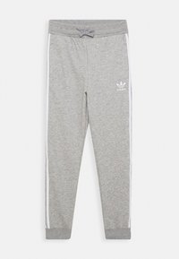 Šedé teplákové kalhoty vyrobené z měkkého materiálu, s bílými bočními pruhy a elastickým pasem se stahovací šňůrkou. Logo Adidas na levém stehně.