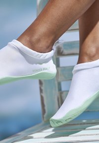 Bottines blanches avec une semelle verte, un ajustement serré autour de la cheville, et "VENICE BEACH" imprimé sur le côté en vert. Texture lisse.