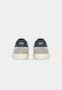 Sneakers met een combinatie van grijs suede en marineblauw synthetisch materiaal, met een witte middenzool en het 'JACK & JONES' logo op de hiel.