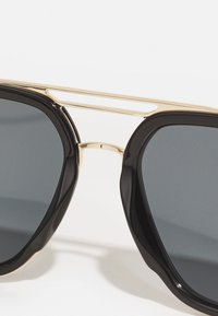 Ochelari de soare negri cu un cadru din metal lucios de culoare aurie; lentile unghiulare; textură netedă; accentuați cu un design îngust al podului.