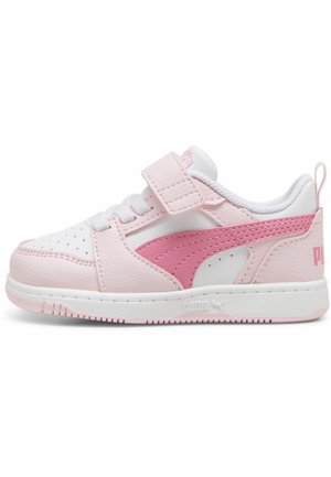Chaussure de sport rose avec des accents blancs, en cuir synthétique. Elle dispose d'une sangle Velcro, de perforations et d'une semelle texturée.