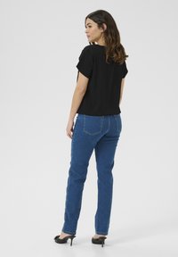 Black short-sleeved top paired with blue straight-leg jeans. The outfit is complemented by black high-heeled shoes. Simple, casual design.