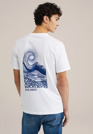 Valge puuvillane T-särk, mille seljal on sinine graafiline print lainetest ja päikesest, allosas tekst "BLUE RIDGE".