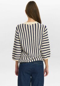 Strickpullover mit Marine- und Creme-Streifen, rundem Halsausschnitt und Dreiviertelärmeln. Texturiertes Material mit einem Knopfdetail auf der Rückseite.