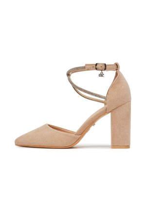 Beżowy zamszowy but na obcasie typu słupek, z noskiem w szpic, paskiem wokół kostki ozdobionym kryształkami oraz małym zawieszonym na klamrze wisiorkiem "DZ".