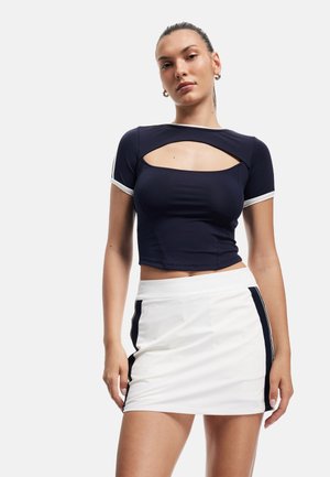 Marineblauw kort topje met een uitsnijding, witte trim, gecombineerd met een witte minirok met marineblauwe zijkanten en een gladde textuur.
