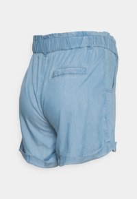 Calções de ganga azul claro com uma cintura elástica, bolso lateral e detalhe de bainha dobrada, apresentando uma textura suave e um design casual.